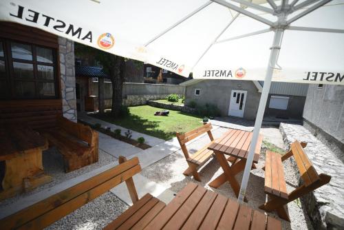 a patio with two wooden benches and an umbrella at Cabarkapa Guesthouse in Žabljak