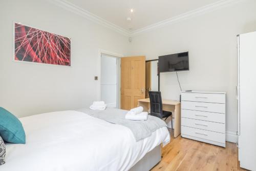 a bedroom with a white bed and a desk at Tulse Hill Luxury Cosy Rooms in London