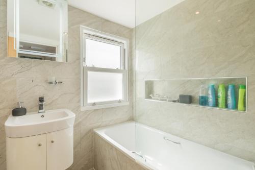 a bathroom with a sink and a bath tub and a window at Tulse Hill Luxury Cosy Rooms in London