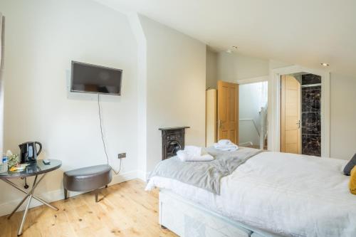 a white bedroom with a bed and a television at Tulse Hill Luxury Cosy Rooms in London