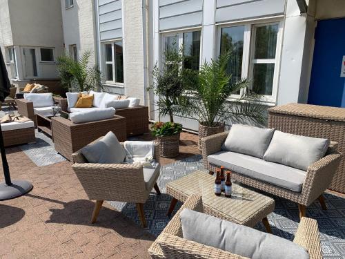 a patio with wicker chairs and couches and tables at Hotell Erikslund in Ängelholm