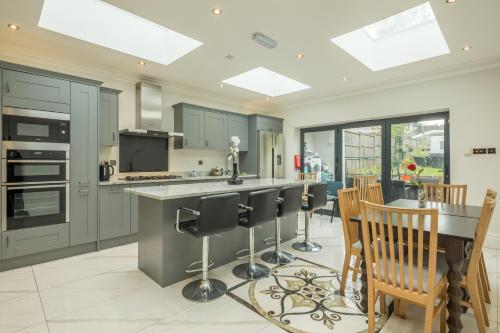 a kitchen with gray cabinets and a table and chairs at Tulse Hill Luxury Cosy Rooms in London
