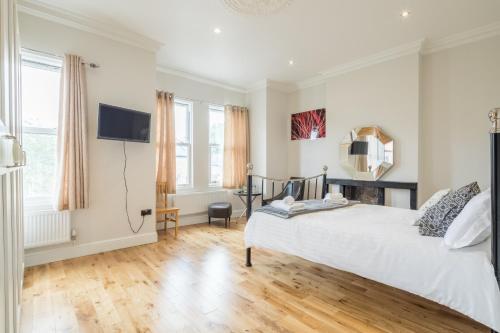 a bedroom with a white bed and a television at Tulse Hill Luxury Cosy Rooms in London