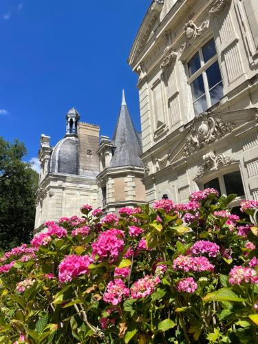 un edificio con flores rosas delante de él en Château le Fresne, en Bouchemaine