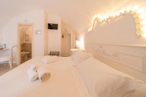 a white bedroom with two towels on a bed at B&B Centro Storico in Otranto