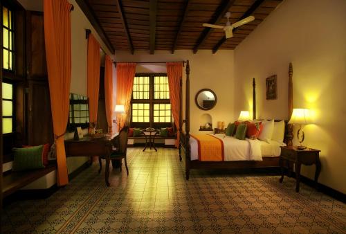 a bedroom with a bed and a desk and a window at Forte Kochi in Cochin