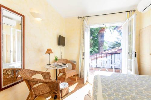 - une chambre avec un lit, une table et un balcon dans l'établissement Hotel Villa Provencale, à Cavalaire-sur-Mer