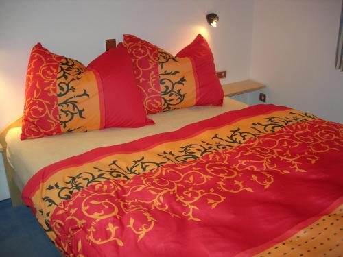 ein Bett mit roten und gelben Decken und Kissen in der Unterkunft Ferienwohnung Kogler in Strobl