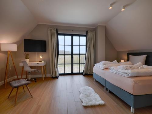 a bedroom with a bed and a desk and a television at Reetland am Meer - Premium Reetdachvilla mit 3 Schlafzimmern, Sauna und Kamin F27 in Dranske