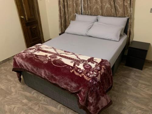 a bedroom with a large bed with a burgundy blanket at Top Base Apartments in Accra