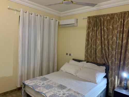 a bedroom with a bed and a window with curtains at Top Base Apartments in Accra