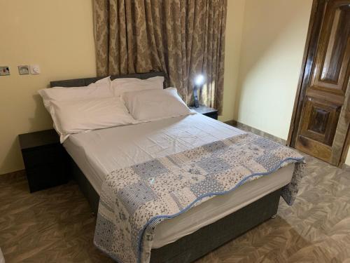 a bedroom with a bed with a blue and white quilt at Top Base Apartments in Accra