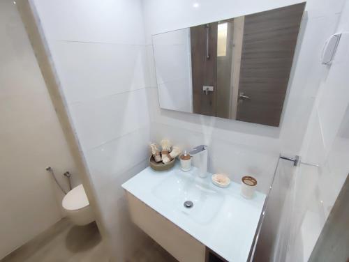 a white bathroom with a sink and a mirror at Ideal Appart El Wahat VIP in El Aouina