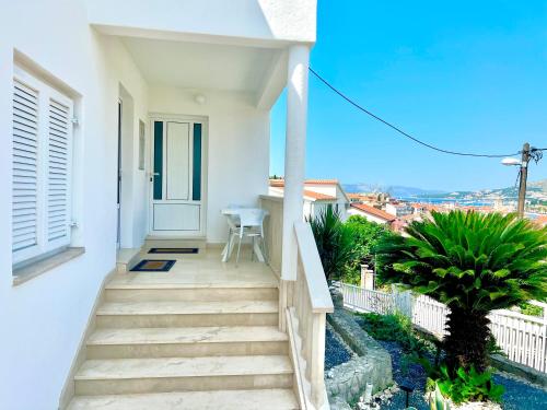 uma casa branca com escadas que levam a uma varanda em Apartments MDK Kate em Trogir