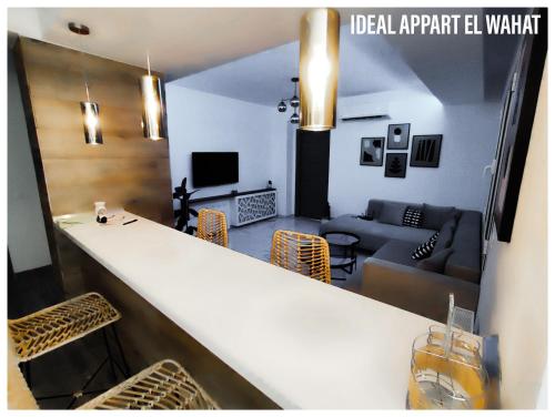 a kitchen and living room with a bar and a couch at Ideal Appart El Wahat VIP in El Aouina
