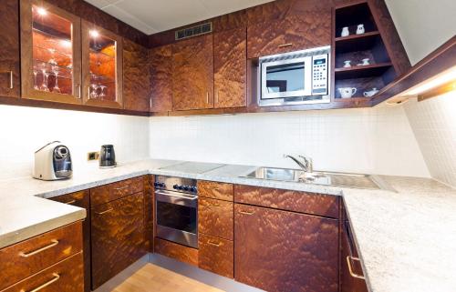 a kitchen with wooden cabinets and a microwave at Living Hotel Großer Kurfürst in Berlin