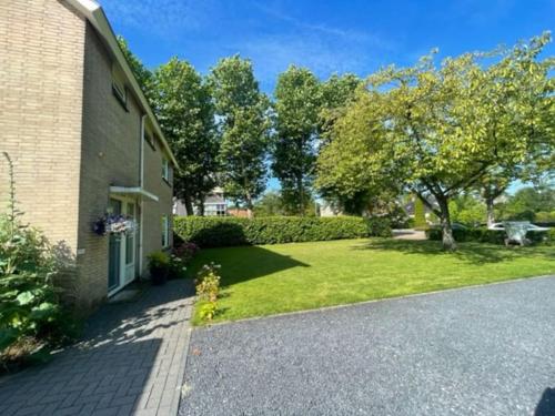 a house with a grass yard next to a building at HolidayHome Zonnestraal 9p Amsterdam and the beach in Heerhugowaard