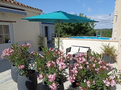 une terrasse avec un parasol bleu et quelques fleurs dans l'établissement Maison Marin, Charming Village Cottage with Pool, à Saint-Thomas-de-Cônac