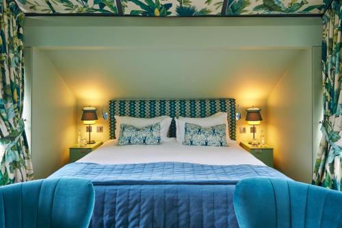 a bedroom with a bed and two blue chairs at Hotel du Vin Exeter in Exeter
