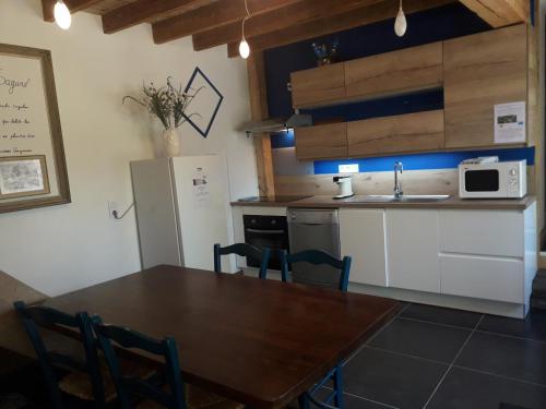 a kitchen with a table and a sink and a refrigerator at Gites, les Sapins, les Jonquilles, le Sagard nature et détente in La Houssière