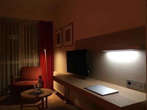 a room with a desk with a television and a chair at Landhotel Broda in Neubrandenburg