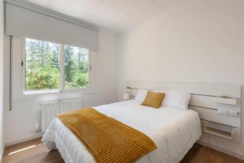 a white bedroom with a bed and a window at L'aviador de Can Ton, in the middle of nature with its own stream in Sant Llorenc Savall