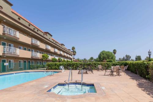 a pool with tables and chairs next to a building at Travelodge by Wyndham Sylmar CA in Sylmar