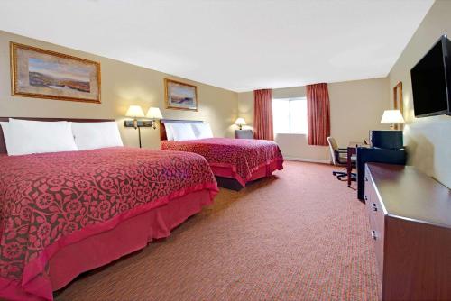 a hotel room with two beds and a flat screen tv at Days Inn by Wyndham St. Louis/Westport MO in Maryland Heights