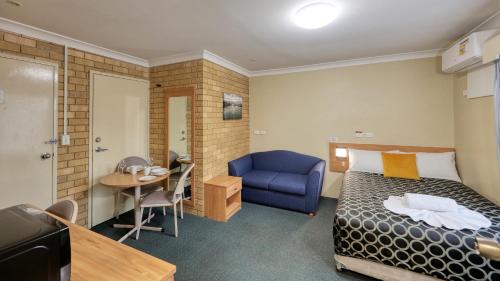 a hotel room with a bed and a blue chair at Forest Lodge Motor Inn & Restaurant in Dubbo