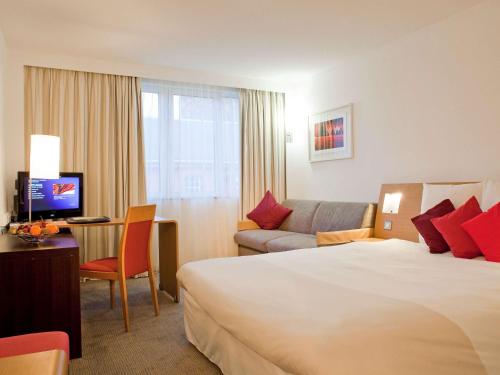 una camera d'albergo con un grande letto e un divano di Novotel Paris Pont De Sevres a Sèvres
