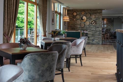a dining room with tables and chairs and windows at Oulton Hall Hotel, Spa & Golf Resort in Leeds