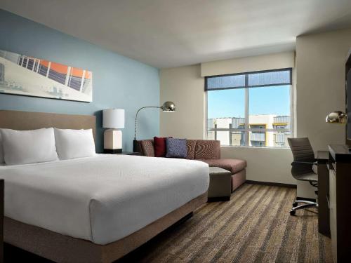 a hotel room with a large bed and a desk at Hyatt House LA - University Medical Center in Los Angeles