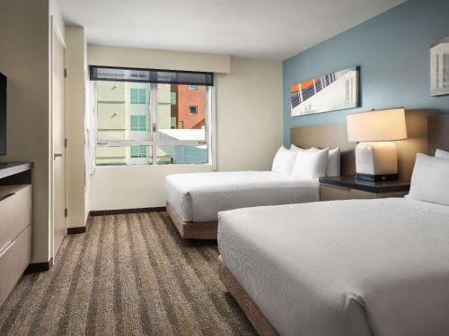 a hotel room with two beds and a window at Hyatt House LA - University Medical Center in Los Angeles