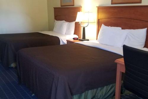 a hotel room with two beds and a chair at Super 8 by Wyndham Vancouver East in Vancouver