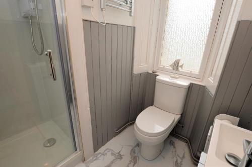 a bathroom with a toilet and a shower and a window at Findhorn Upper Apartment in Kames