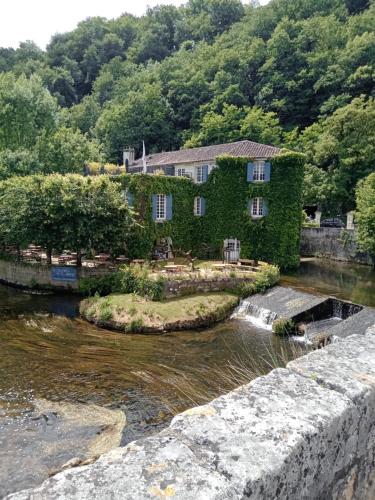 an ivy covered house next to a river at Chez Goret Gites - Gite Skippy Couples only in Courgeac