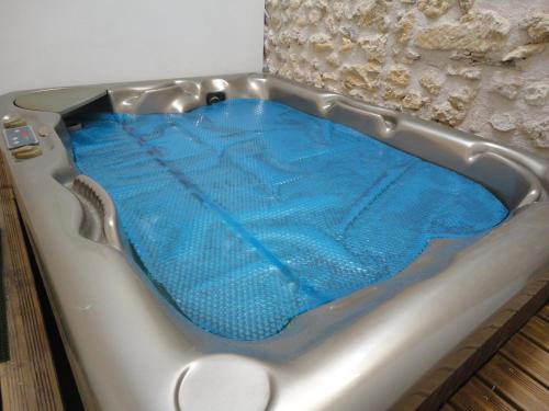 a bath tub filled with blue water in a room at Chez Goret Gites - Gite Skippy Couples only in Courgeac