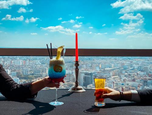two people holding glasses of drinks on a table with a view at Kenzi Tower Hotel in Casablanca