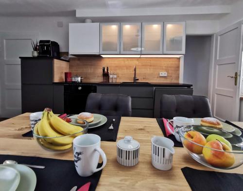 a wooden table with bowls of fruit on top of it at Neues City Center Piano Appartement mit Netflix in Klagenfurt