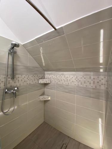 a bathroom with a shower with white tiled walls at Centrum Vendégház in Tihany