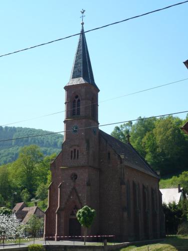 an old church with a steeple with a clock on it at Gîte Hecker Alsace in Niedersteinbach