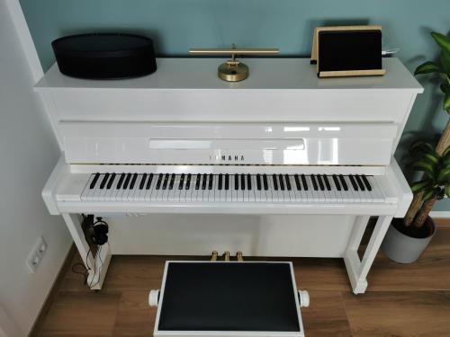a white piano in a room with a keyboard at Neues City Center Piano Appartement mit Netflix in Klagenfurt