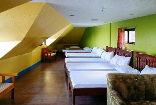 a row of beds in a room with green walls at RedDoorz Hostel @ Baguio Tourist Cabin in Baguio