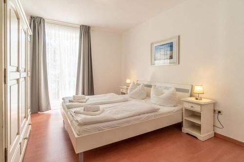 een slaapkamer met een bed met witte lakens en een raam bij Neubau-Villa-Strandidyll-Typ-4-Apartment-1-2 in Binz