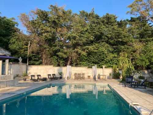 une piscine avec des chaises et des tables dans l'arrière-cour dans l'établissement Gîte Comme à la maison, à Hyères