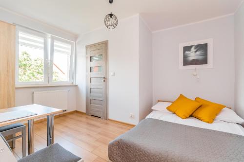 a bedroom with a bed with yellow pillows and a table at Pokoje Gościnne Lipowa in Sztutowo