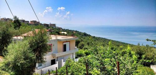 une maison sur une colline avec l'océan en arrière-plan dans l'établissement Amazing View Apartments at Kroi i Gjine, Piqeras, à Piqeras