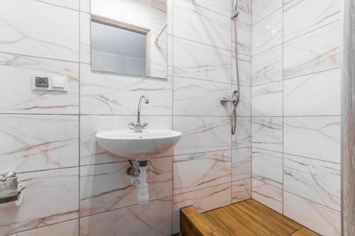a white bathroom with a sink and a mirror at Pokoje Gościnne Lipowa in Sztutowo