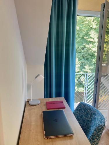 a laptop sitting on a wooden table next to a window at Grand Park rooms & apartments in Čačak