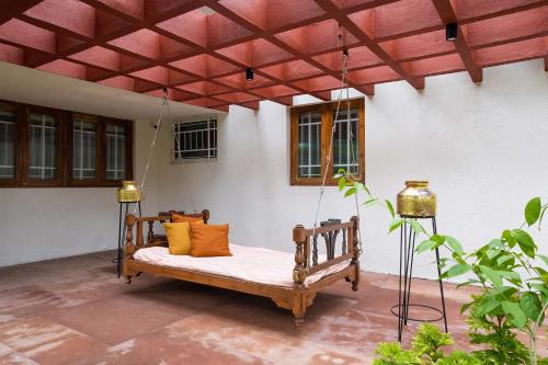 ナーシクにあるStayVista's Villaggio - Orchard Oasis with Pool, Expansive Lawn, Patio & Indoor Activitiesのパティオ(オレンジ枕付きのポーチブランコ)